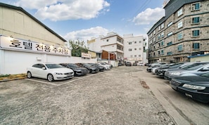 A parking lot with multiple cars, a building with a sign in Korean, and a clear sky.