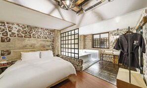 A bedroom with a large bed, a bathroom with a bathtub, and a robe hanging on a rack. - Brown Dot Dongseong-ro (Daegu)