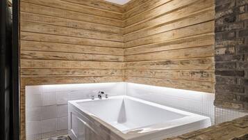 Un baño moderno con una bañera grande, paneles de madera y suelo de baldosas.
