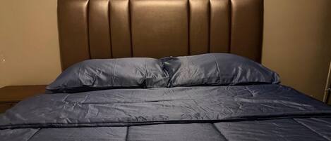 Una cama con cabecera acolchada y dos almohadas.