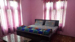 Un dormitorio con cama, una mesita, una silla y cortinas.