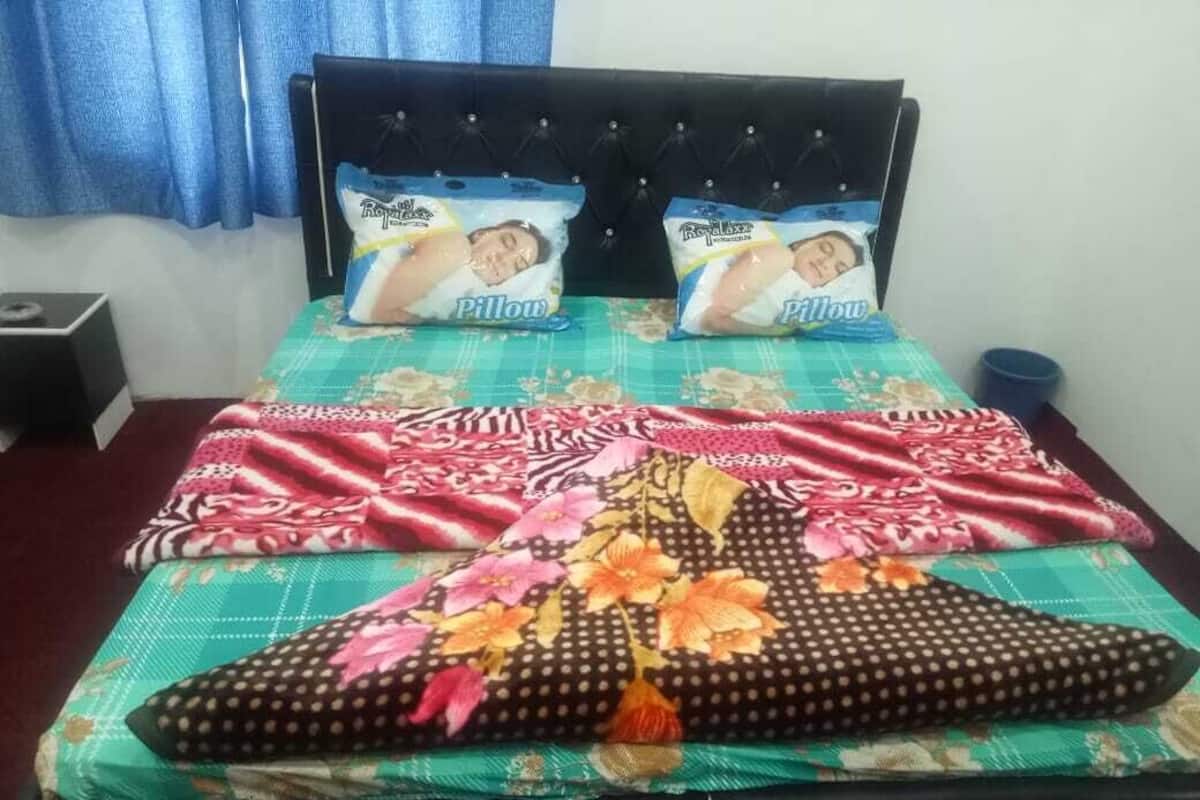 Uma cama com roupa de cama florida, duas almofadas e cabeceira.