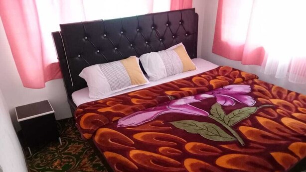 Una cama con colcha estampada, cabecero acolchado y mesita de noche.