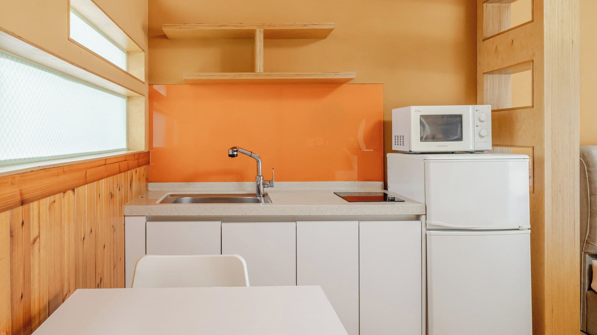 Cozinha compacta com pia, micro-ondas e geladeira.