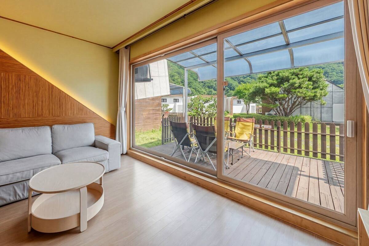 A modern living room with a sofa, a round coffee table, and a large sliding glass door leading to an outdoor deck.