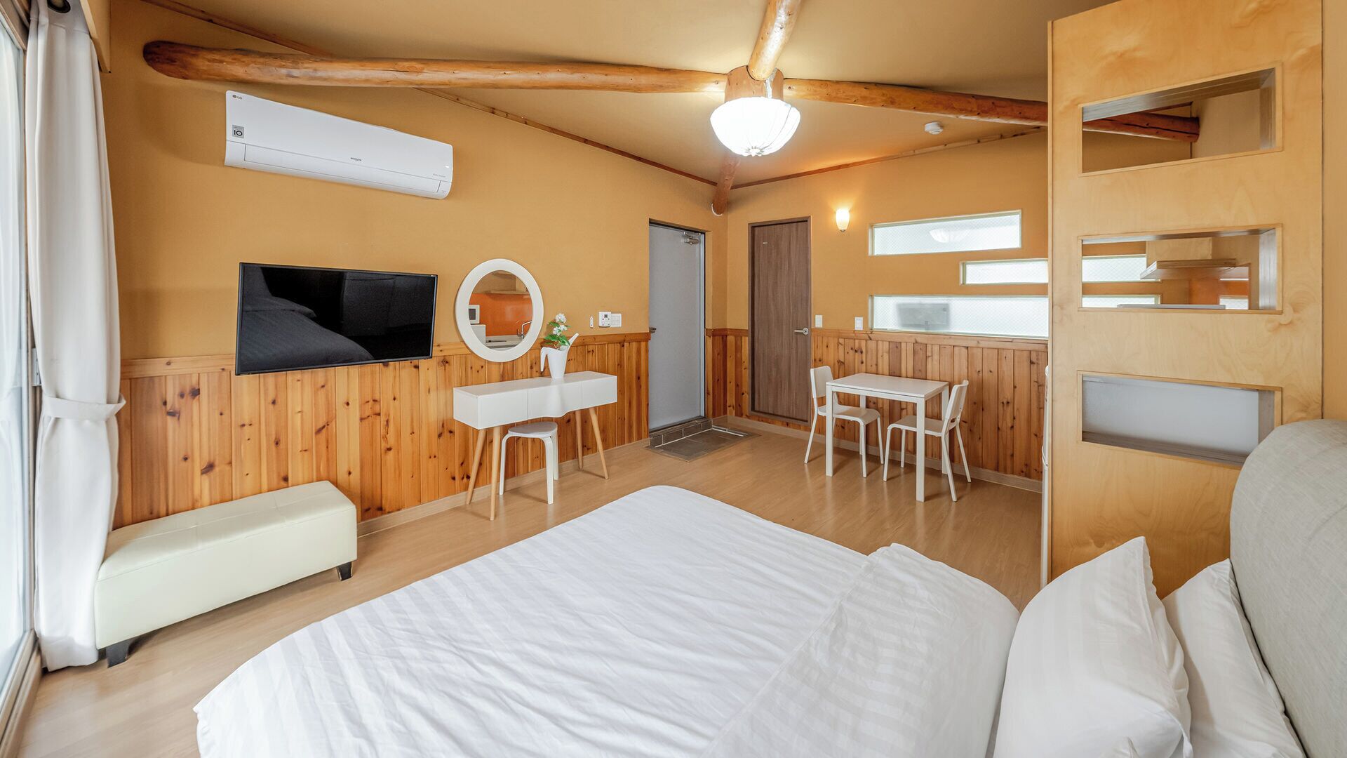 Una habitación con cama, escritorio, silla, espejo y ventana.