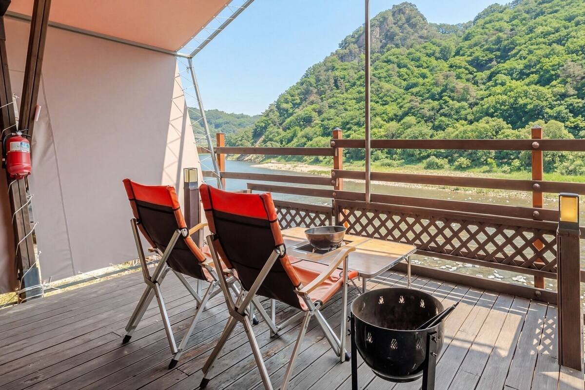 A balcony with a table, chairs, and a black bucket.