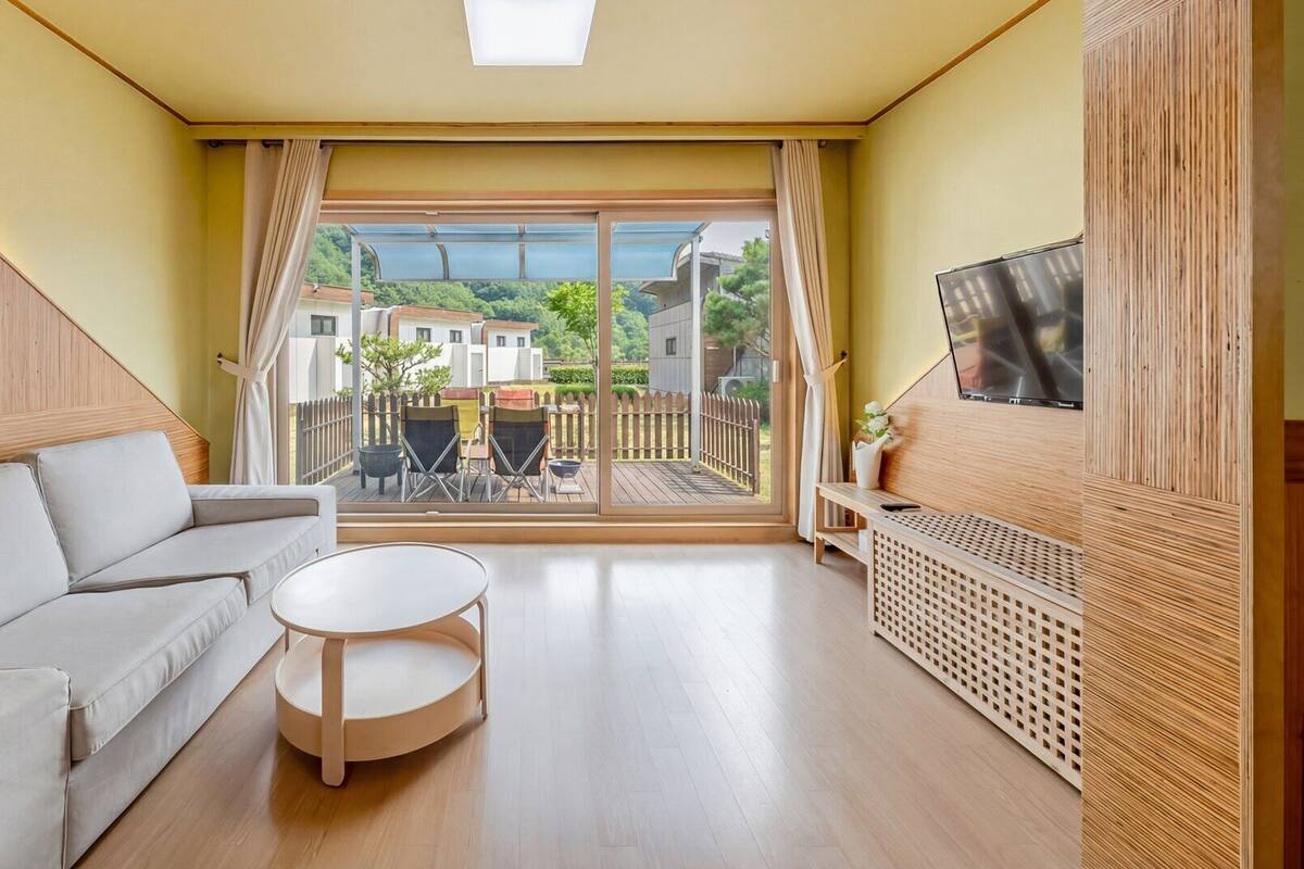 A modern living room with a sofa, a round table, and a TV mounted on the wall.