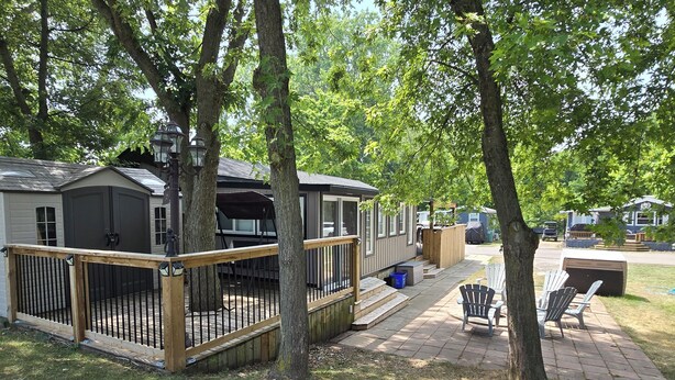 A decked outdoor area with a covered seating area, a small shed, and a wooden fence. - Freshly remodeled premium trailer in prime location! (Port Colborne)