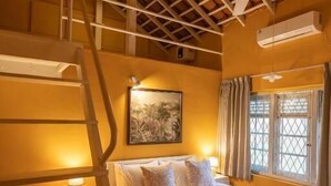 A bedroom with a bed, a nightstand, a ladder, a ceiling fan, and a window with curtains. - Heuvel Villa Kandy (Kandy)