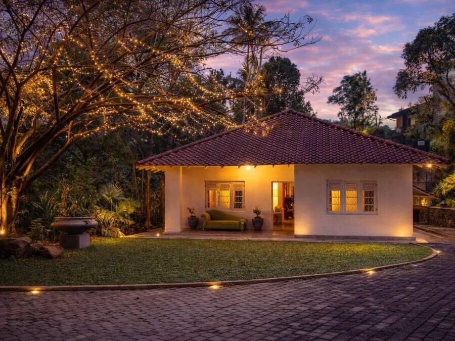 A house with a tiled roof, a lawn, and a paved driveway.