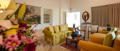 A living room with a sofa, armchairs, a coffee table, and a painting on the wall.
