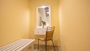 A small room with a white bench, a chair, a white dresser, and a mirror with a vase of flowers. - Heuvel Villa Kandy (Kandy)