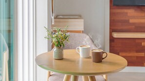 A round wooden table with a vase of flowers, two coffee cups, and a wooden wall with a bench in the background. - Goseong Natural House Pension (Goseong)