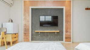 A modern bedroom with a television mounted on a textured wall, a wooden nightstand, a chair, and a bed. - Goseong Natural House Pension (Goseong)