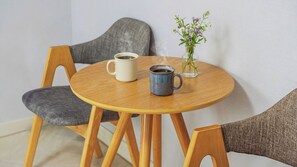 A round wooden table with two ceramic mugs and a glass vase with flowers. - Goseong Natural House Pension (Goseong)
