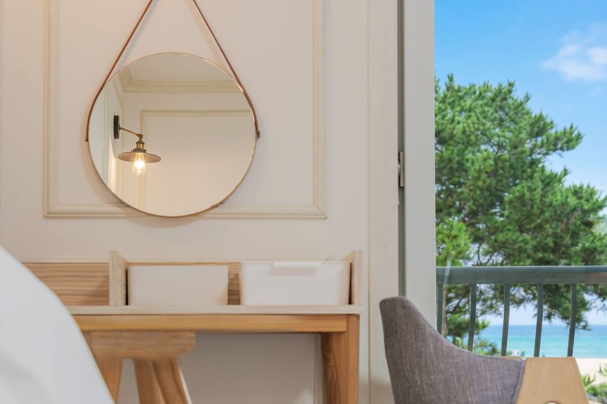 Une pièce avec un bureau en bois, un miroir suspendu et une vue sur la mer.
