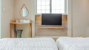 Habitación de hotel con dos camas, un televisor instalado en una pared de madera, una mesita y un espejo.