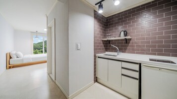 A modern kitchen with a brick backsplash, a built-in dishwasher, and a window overlooking a green landscape.