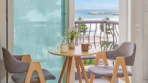 Un balcon avec une table, deux chaises, un vase de fleurs et deux tasses.