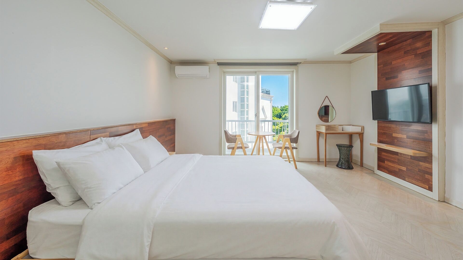 Quarto de hotel com cama, televisão, mesa pequena e uma cadeira.