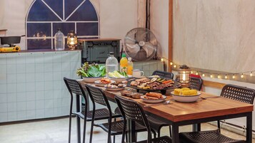 Una mesa de comedor con varios platos, sillas, un ventilador y un farol.