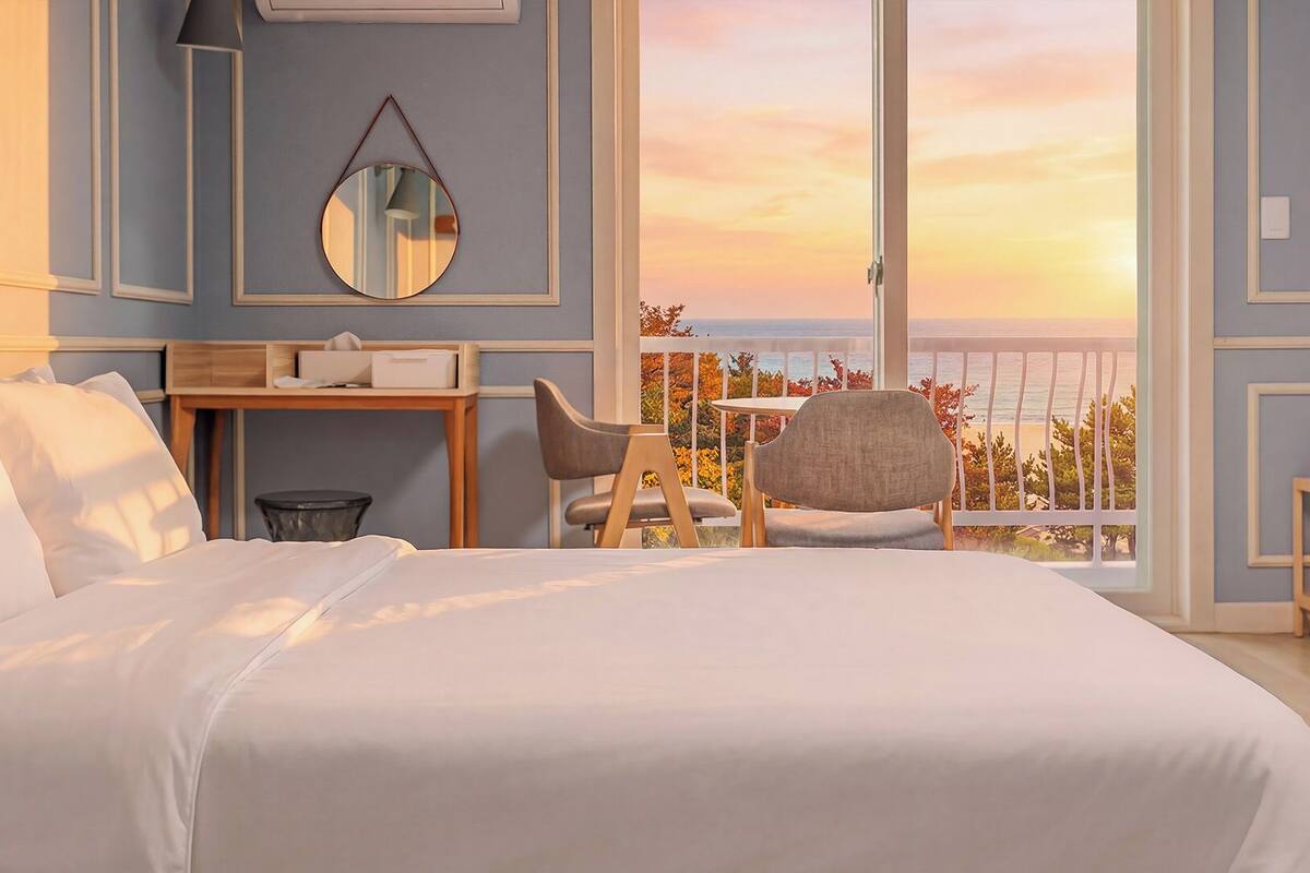 Une chambre à coucher avec un grand lit, un bureau, une chaise, une petite table et un balcon avec vue.