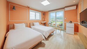 Ein Hotelzimmer mit zwei Betten, einem kleinen Tisch, einem Stuhl, einem Kühlschrank und einem Balkon mit Blick.
