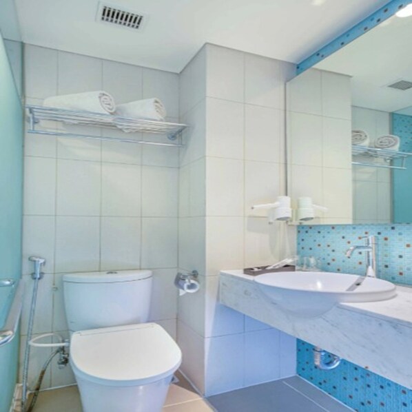 A bathroom with a toilet, sink, mirror, and towel rack. - Asyana Pemuda Jakarta (Jakarta)