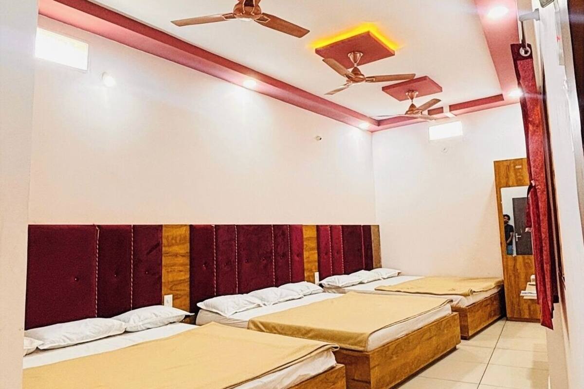 Habitación de hotel con cuatro camas, techo rojo y ventiladores de techo.