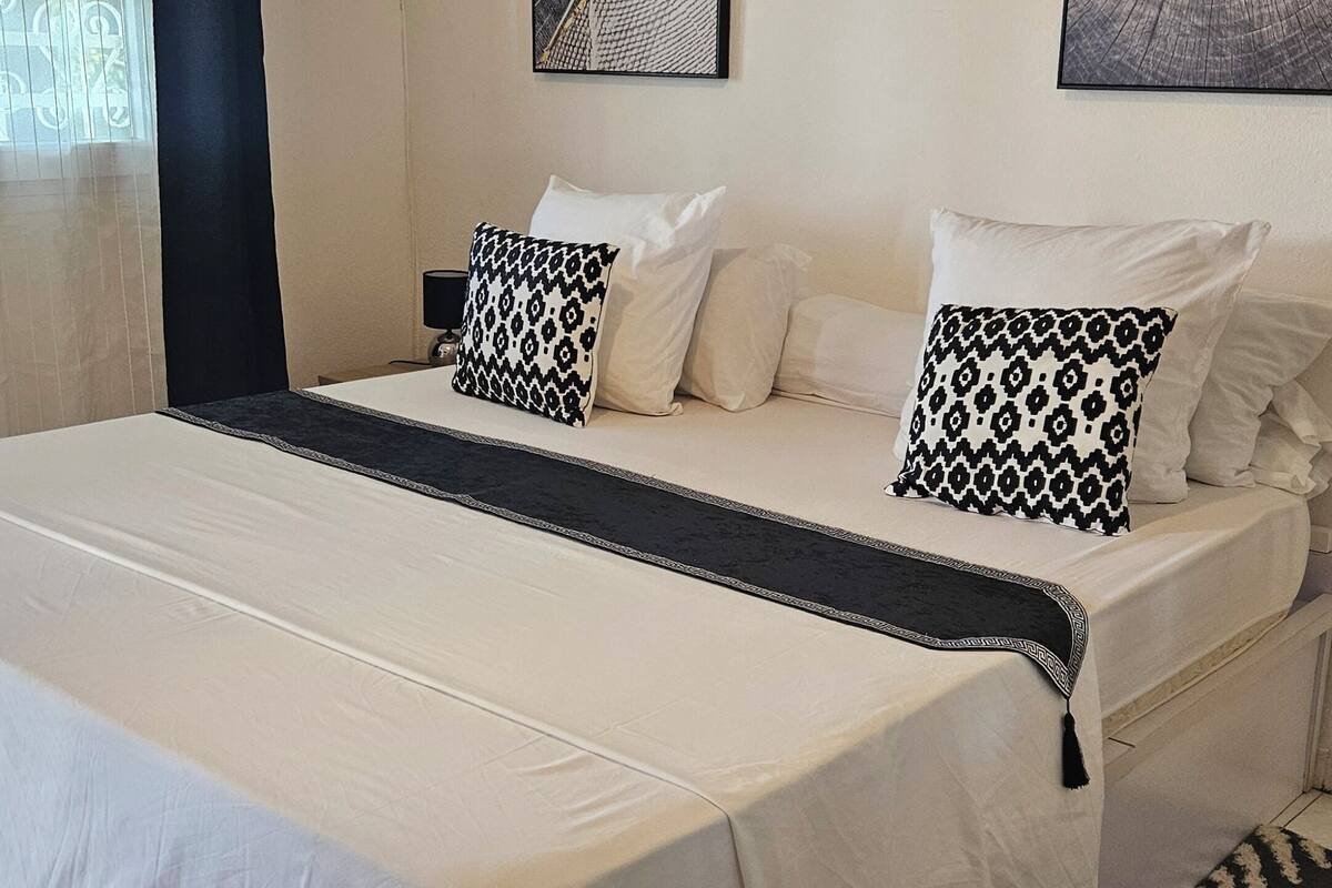 A bedroom with a bed, pillows, a nightstand, and wall art.
