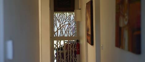 A hallway with a decorative screen, a fire extinguisher, and artwork on the walls.