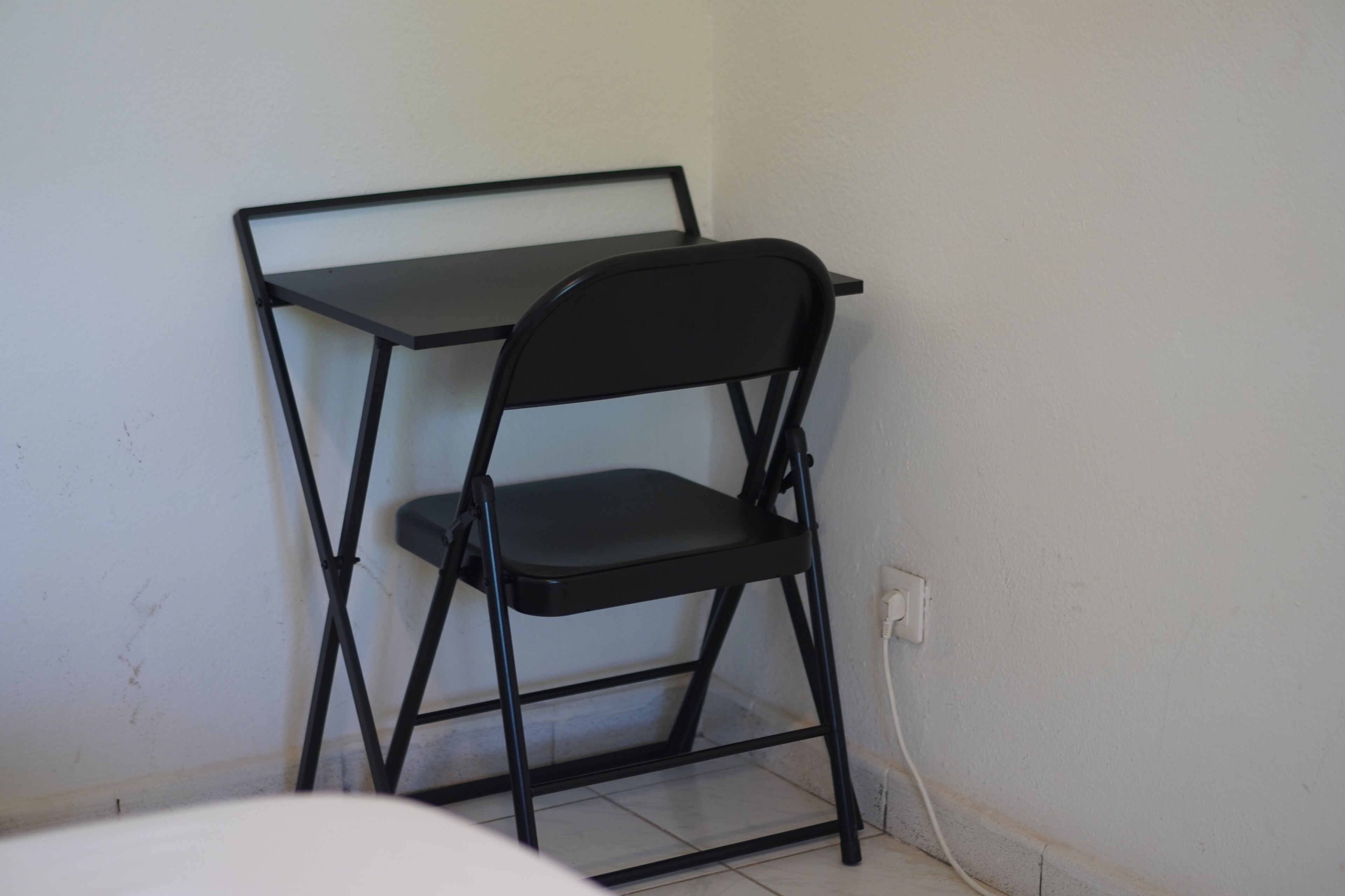 Een zwart metalen bureau met een stoel in een hoek van de kamer.
