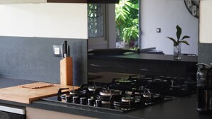 A modern kitchen with a gas stove, wooden cutting board, and a knife block.