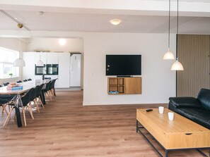 Ein modernes Wohnzimmer mit Couchtisch aus Holz, einer schwarzen Ledersofa und einem flachbildfernseher an der Wand.