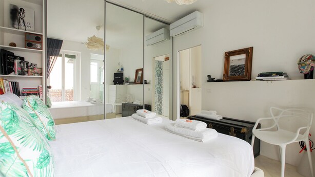 A hotel room with a large bed, a wardrobe, a mirror, a bookshelf, and a desk with a chair. - De Angeli 60-square-meter apartment - M1 & M4 - near CityLife, Tortona district, San Siro (Milano)