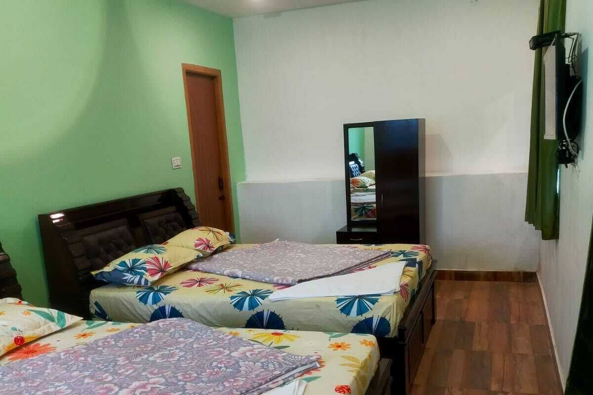 Une chambre avec deux lits, une télévision et un plancher en bois.