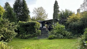 A well-maintained garden with a wooden staircase leading to a house, surrounded by dense greenery. - Fully modernized in 2026, 1 minut from the ocean (Børkop)