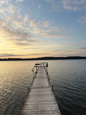A wooden pier extending into calm water with a clear sky above.