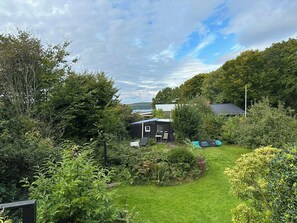 Une propriété située en zone rurale, comprenant une petite cabane, une pelouse verdoyante et de nombreux arbres.
