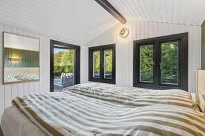 A bedroom with a large bed, two windows, a ceiling light, and a view of greenery outside. - Fully modernized in 2026, 1 minut from the ocean (Børkop)