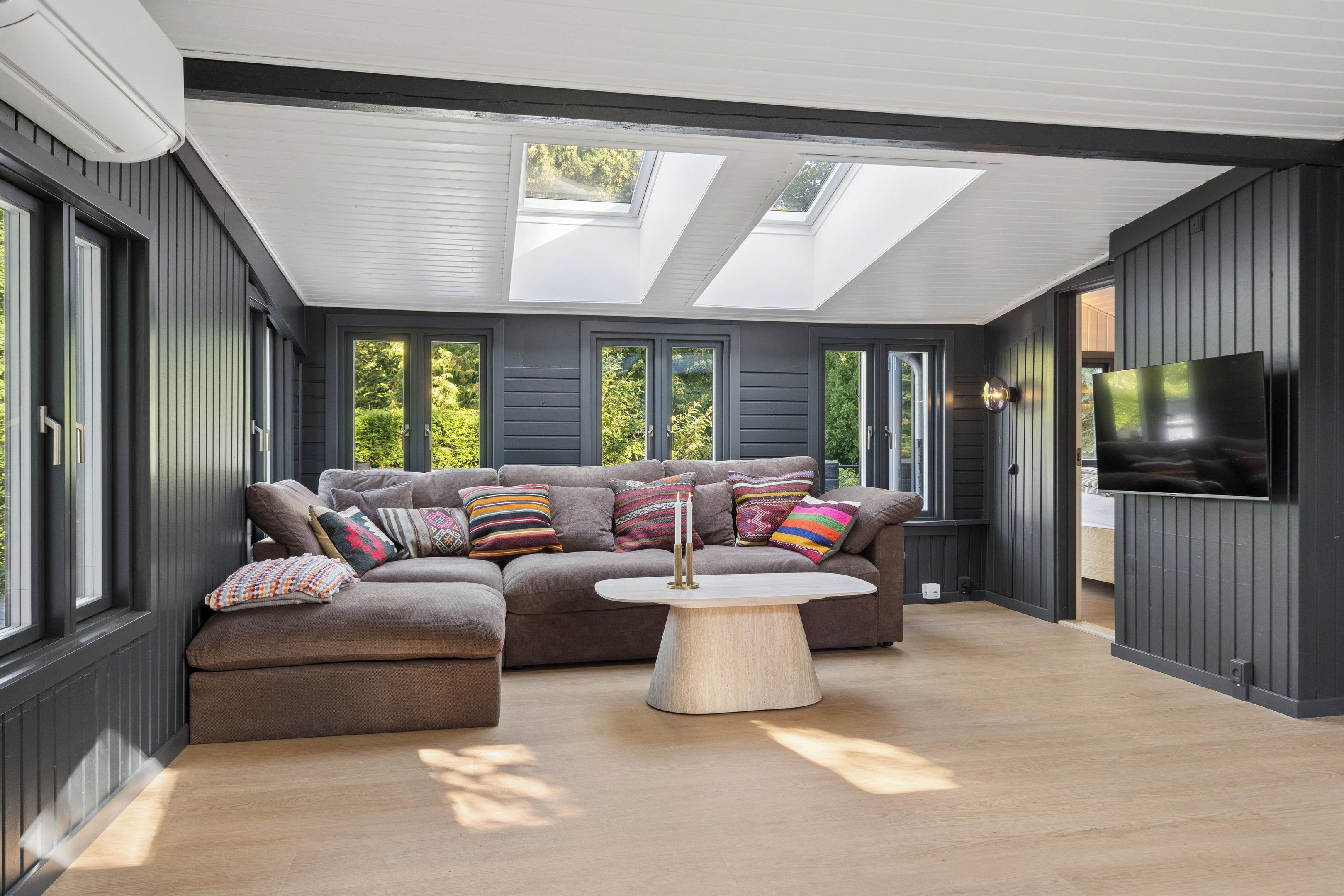 A modern living room with a sectional sofa, a coffee table, and a flat-screen TV.