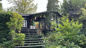 A wooden house with a porch, surrounded by lush greenery and a wooden staircase leading to the entrance. - Fully modernized in 2026, 1 minut from the ocean (Børkop)