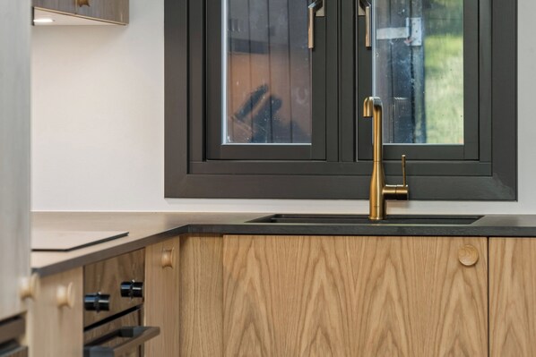 A kitchen with a modern faucet, wooden cabinets, and a window above the sink.