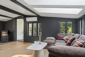A modern living room with a built-in fireplace, a sofa set, and a skylight.
