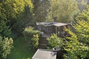 A house surrounded by dense trees, with a visible deck and outdoor seating area.