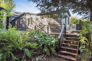 A wooden cabin with a wooden staircase leading up to a deck.