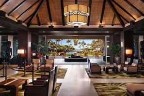 A spacious lobby with a view of a pool and palm trees, featuring a high ceiling with a central light fixture and multiple seating areas. - Beachfront Westin Kā‘anapali Resort + Amenities . STUDIO (Lahaina)