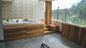 A modern bathroom with a wooden vanity, a freestanding bathtub, and a view of a forested area. - Saya Hotel & Suites (Sayausi)