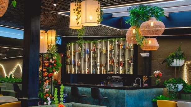A bar area with a counter, seating, and hanging lights. - Saya Hotel & Suites (Sayausi)